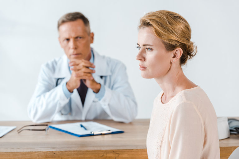 woman sitting near doctor in white coat