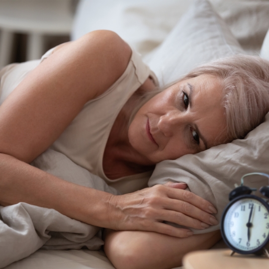 insomnia Woman in bed stares at clock struggling to sleep