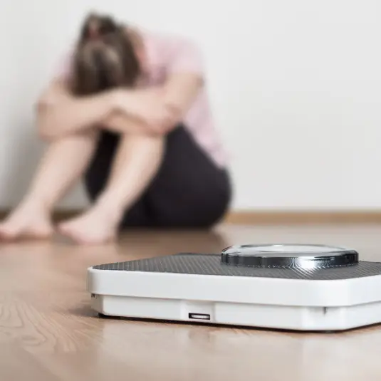 difficulty-losing-weight Upset woman sitting behind scales