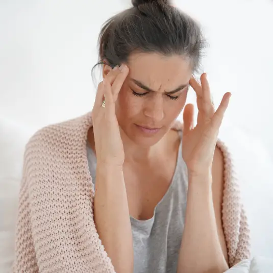 headache Woman puts hands to temples during headache