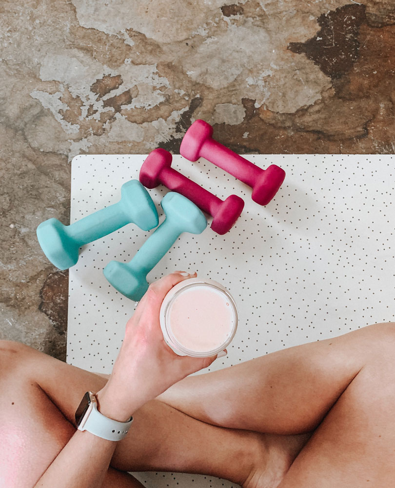 Woman sits on a yoga mat with smoothie