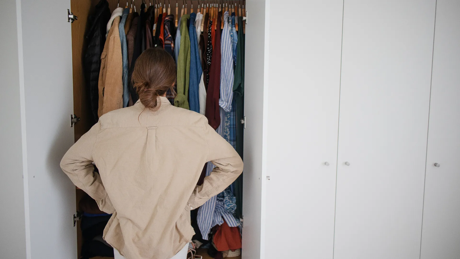 Dress to Flatter Your Figure - woman looking at her closet full of clothes